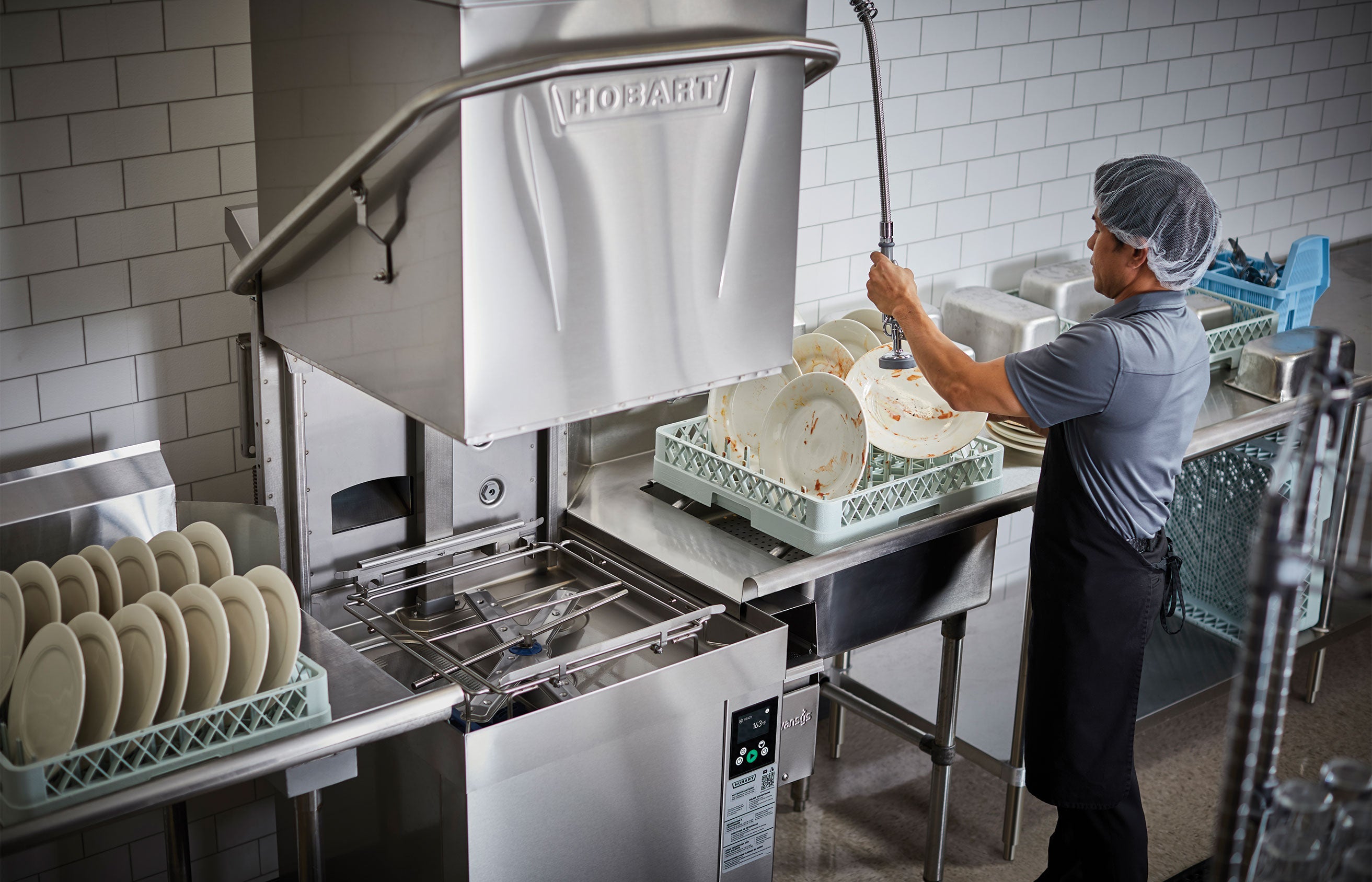 Man washing dishes with a Hobart Door Type Dishwasher